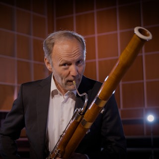 Ein Mann spielt Fagott. Das Instrument gehört zu den Holzblasinstrumenten.