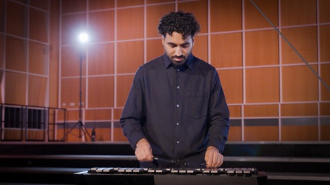 Ein Orchestermusiker spielt auf einem großen Glockenspiel. Dieses Instrument gehört zur Gruppe der Schlaginstrumente.