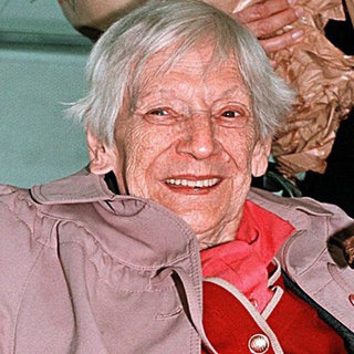 Emilie Schindler, die Witwe von Oskar Schindler, im Jahr 1999. Die grauhaarige Frau sitzt im Rollstuhl und hat Blumen auf dem Schoß.