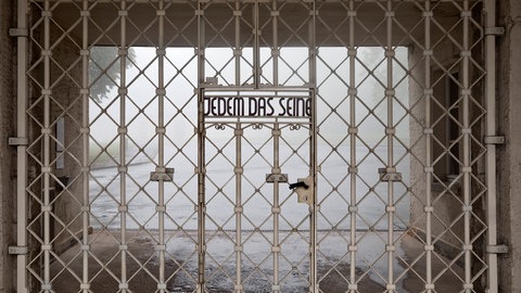 Der Schriftzug „Jedem das Seine“ auf dem weißen Gitter des Eingangs zum Konzentrationslagers Buchenwald. Der Ausdruck hat seit dem Nationalsozialismus eine negative Bedeutung.