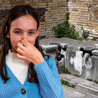Im Hintergrund die Ruinen einer Toilettenanlage der alten Römer; im Vordergrund ein Mädchen, das sich die Nase zuhält