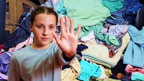 Im Vordergrund ein Mädchen in Abwehrhaltung, im Hintergrund ein großer Haufen bunter Wäsche
