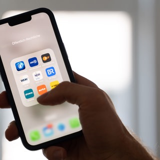 Hand mit Handybildschirm, auf dem verschiedene Apps der öffentlich-rechtlichen Programme zu sehen sind. Wie wichtig sind Medien für die Demokratie und welche Rolle spielen sie?