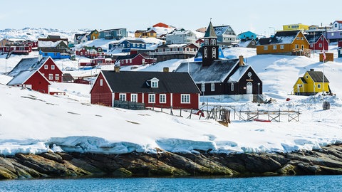 Ansicht der verschneiten Küstenstadt Ilulissat auf Grönland. Warum haben die USA und andere Länder so großes Interesse an Grönland?