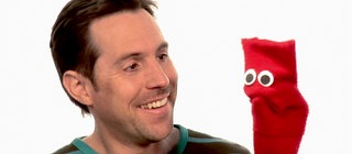 Englisch für die Grundschule: David spricht mit der roten Strumpfhandpuppe Red.