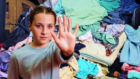 Im Vordergrund ein Mädchen in Abwehrhaltung, im Hintergrund ein großer Haufen bunter Wäsche