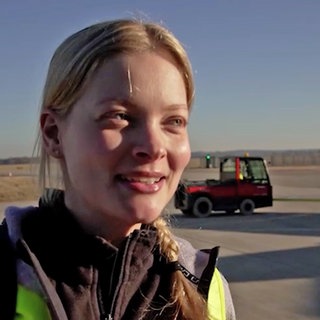 Eine junge Frau lächelt während eines Interviews in die Kamera.