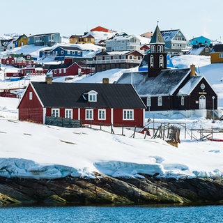 Ansicht der verschneiten Küstenstadt Ilulissat auf Grönland. Warum haben die USA und andere Länder so großes Interesse an Grönland?