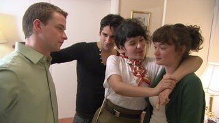 Vier junge Erwachsene stehen beisammen. Sie legen sich gegenseitig die Arme um die Schulter.