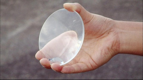 Eine Hand hält eine Lupe.