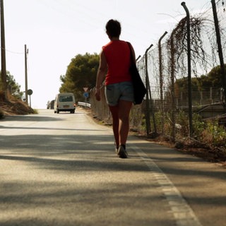 Eine Frau läuft auf einer Landstraße.