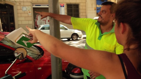 Zwei Menschen stehen auf der Straße und zeigen mit ausgestrecktem Arm in die selbe Richtung.