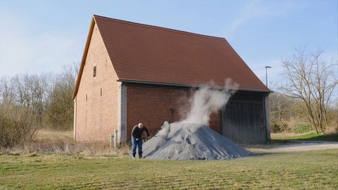 Mann mit Gesteinsstaub auf einem Acker.