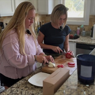 Lily und eine Freundin schneiden in der Küche Gemüse und Mozzarella