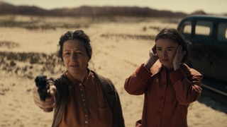 Spielszene: Golda Meir will ihr Land Israel verteidigen. Sie macht Schießübungen in der Wüste; ihre Tochter steht neben ihr und hält sich die Ohren zu.