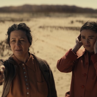 Spielszene: Golda Meir will ihr Land Israel verteidigen. Sie macht Schießübungen in der Wüste; ihre Tochter steht neben ihr und hält sich die Ohren zu.