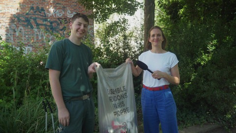 Stefanie und ein Gärtner mit einer Mülltüte in der Hand