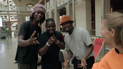 Drei junge schwarze Tänzer lachen in die Kamera