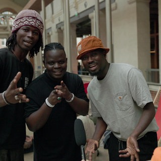 Drei junge schwarze Tänzer lachen in die Kamera