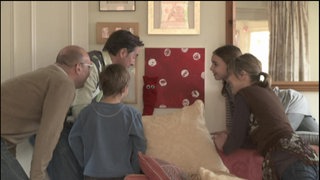 Eine Gruppe Menschen steht versammelt vor einem roten Bild. Eine rote Strumpfhandpuppe hat sich hier versteckt.