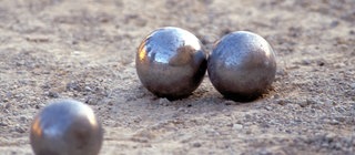 Drei Bocciakugeln auf sandigem Boden