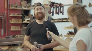 Stefanie mit Mikrofon in der Hand befragt eine Schreiner mit Akkuschrauber in der Hand