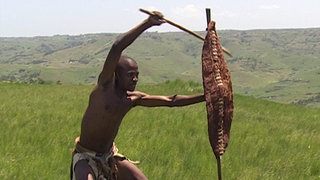 Ein Kämpfer mit Schutzschild in der Hand schwingt seinen Stock