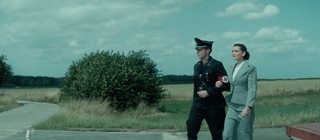 Spielszene: Wernher von Braun in SS-Uniform hat seine Sekretärin untergehakt. Der Ingenieur baut im Zweiten Weltkrieg Raketen für Hitler.