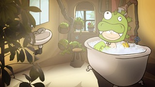 Der kleine Philosoph Knietzsche sitzt in einem grünen Monsterkostüm in einer vollen Badewanne.