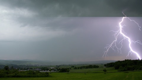 Blitz am blauen Himmel über Silhouette eines Hauses. Wie entsteht ein Gewitter? Was passiet bei Blitz und Donner?