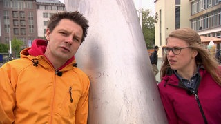 Ein Mann und eine Frau lehnen an einer Säule. 