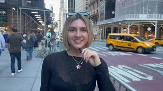 Lily auf einer Straße in New York. Im Hintergrund viele Menschen und gelbe Taxis