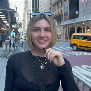 Lily auf einer Straße in New York. Im Hintergrund viele Menschen und gelbe Taxis