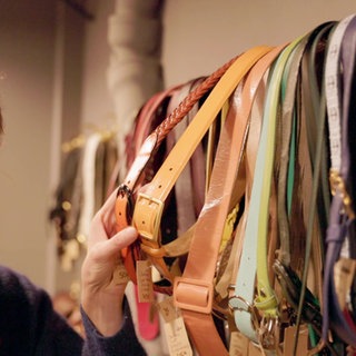 Stefanie mit Mikrofon in der Hand an eienr Wand mit Gürteln