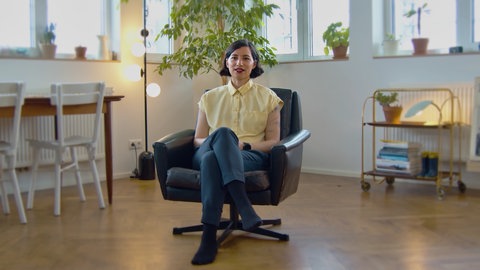 Eine junge Frau gibt sitzend ein Interview.