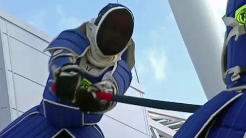 Ein Kämpfer in Schutzkleidung schwingt seinen Stock