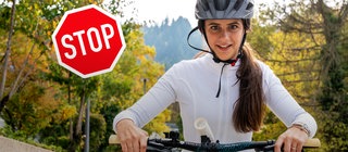 Ein Mädchen fährt mit einem Fahrrad auf die Kamera zu, mit Stoppschild im Hintergrund
