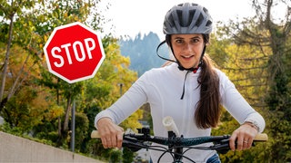 Ein Mädchen fährt mit einem Fahrrad auf die Kamera zu, mit Stoppschild im Hintergrund